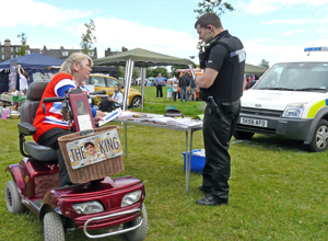 Woman on burgundy mobility scooter talking to officer of Lothian & Borders Police