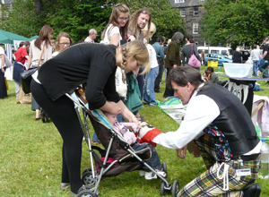 Woman with small child in a buggy and crouching magician in tartan trews