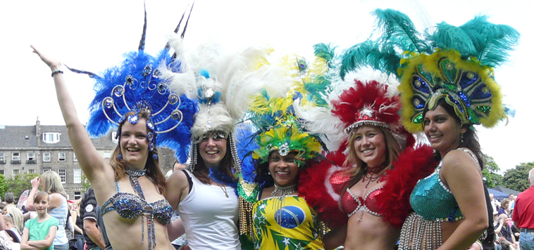 Five women posing in samba costumes with colourful feather head dresses
