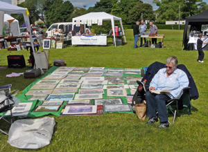 A local artist sits and reads beside  rows of pictures eight deep