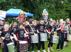 Row of primary school age drummers in black & white Pulse of the Place tee  shirts