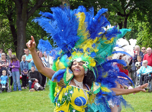 Woman dancing in yellow blue and green costume - the colours of the Brazilian flag with a blue, yellow and green feathered head dress