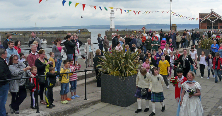 Newhaven villagers watch the Fisher King and Gala Queen walking processing along the  harbour