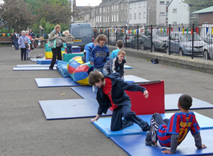 Children jumping and playing on soft play blocks and a tunnel on blue gym mats