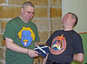 Shaven Dave being presented with a woolie hat with a Saltire on, by Gordon Munro