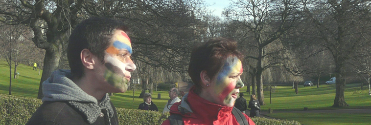 Two young people with faces painted in rainbow colours