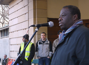 Weyman Bennett in blue raincoat with striped scarf