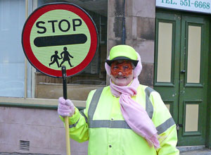 Woman in yellow waterproofs with lollipop, pink scarf and Spider-Man mask