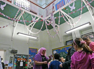 View of entrance hall with pink ribbons hanging down and Headteacher Miss Thomson in a pink wig