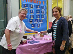 Two women holding up a pink ribbon for sale