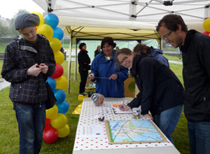 Smiling woman marks out a map of the area as two men look on with curiosity