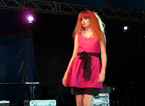 Woman in shocking pink knee length dress with black fabric belt