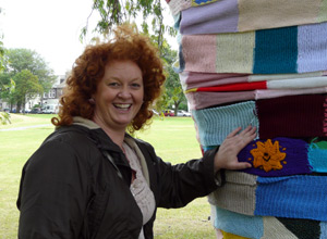 Adele Conn, Leith Festival Manager with a wool clad tree pointing to the Sunshine on Leith square