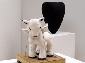 White clay winged lamb in front of a black heart shaped pot
