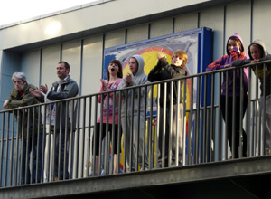 Seven young people watching and cheering from the balcony