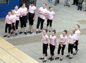 Two rows of primary school age girls in pink tee shirts and black leggings
