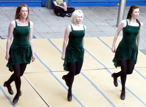 Three women in green dresses dancing with their arms by their sides