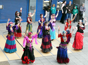 Women dancing American Tribal style in pink, black, blue, red and purple costumes with turbans