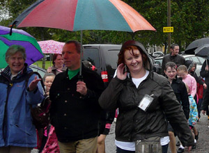 The golf umbrella is red green and orange, Adele is cheerful in her waterproofs