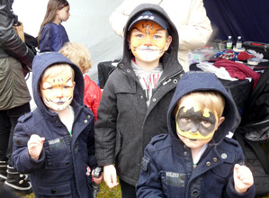 Three boys with an assortment of tiger and Batman themed painted faces