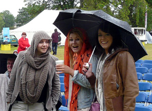 Three young women sheltering under an umbrella