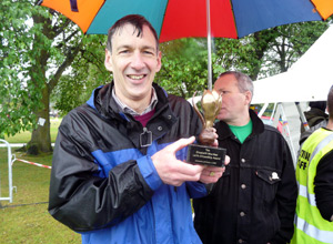 Iain in black and blue anorak posing with his crocus award