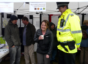 Smiling woman with coffe cup under the gazebo with a member of Lothian & Borders finest