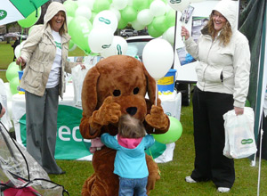 Woman in giant spaniel costumre kneels down to be hugged by a small child
