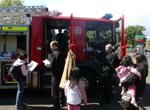 Women and children gathered round a fire engine talking to officers who help children climb out of the cabins