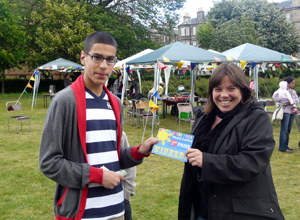 Young man in glasses and striped rugby shirt receives a voucher from smiling woman in black anorak