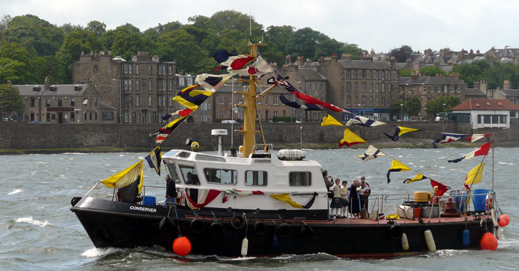Boat with coloured bunting sailing past the tenements along Lower Granton Road with Gala party looking across to Fife