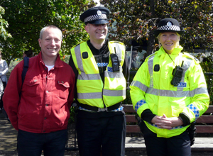 Man in red shirt with two uniformed officers in yellow waterproofs