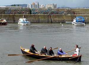 A team of rowers rowing round Newhaven Harbour looking across to Granton