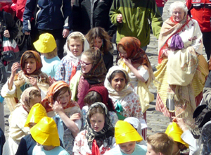 Children with headscarves dressed as fishwives with a white haired woman dressed similarly