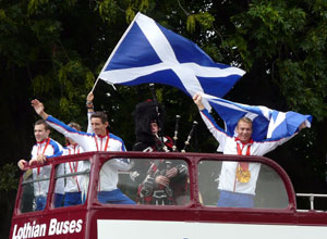 Saltire waving atop the bus with the trees of Holyrood Palace in the background