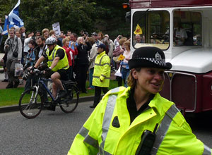 Full figured male officer on a pushbike and female officer smiling and speaking to spectators